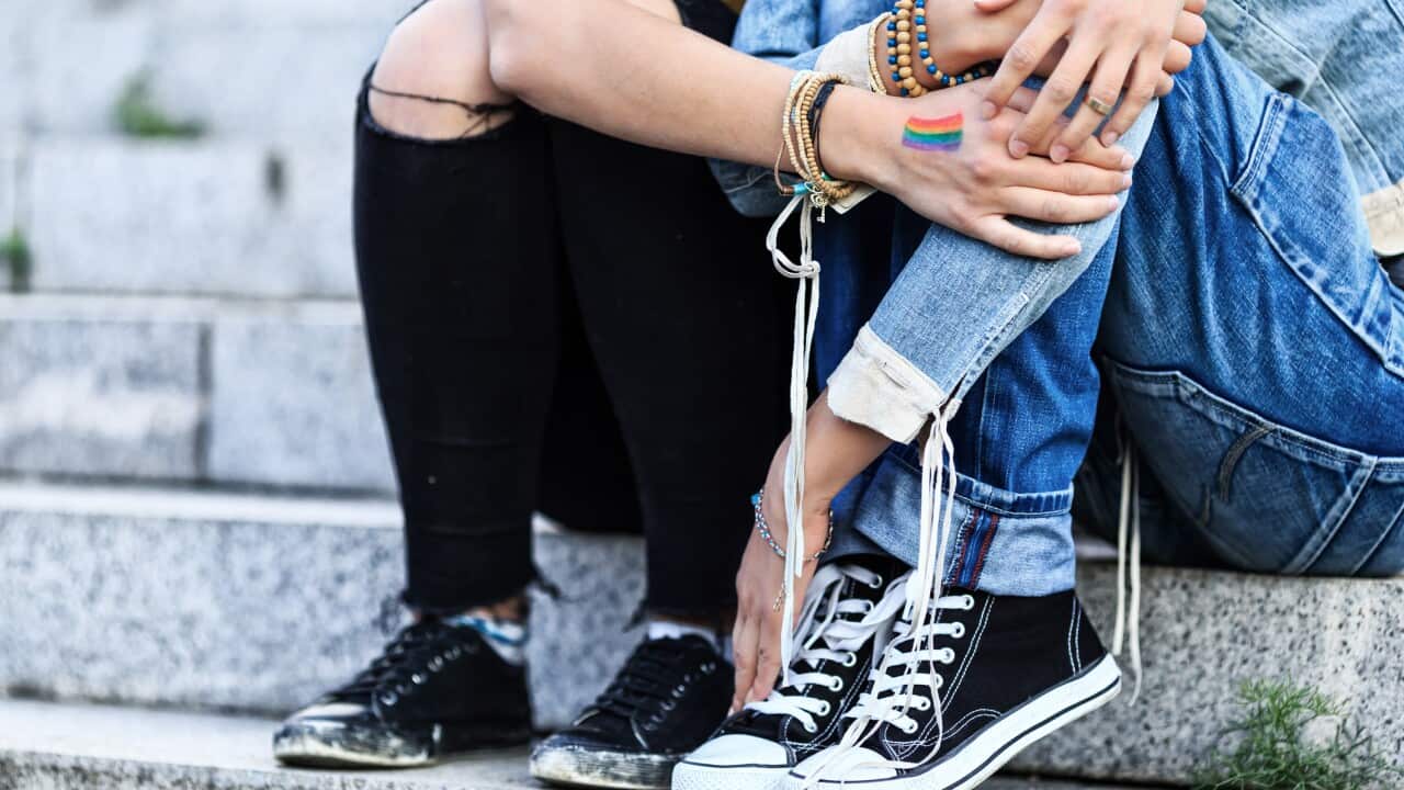 Unrecognizable girls embracing and sitting on stairs.
