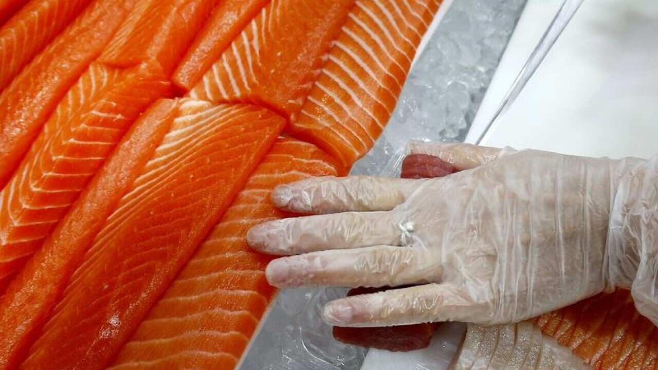 A woman cuts salmon to be sold at a fish store