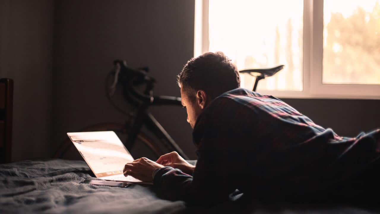 Man using laptop computer lying on bed at home