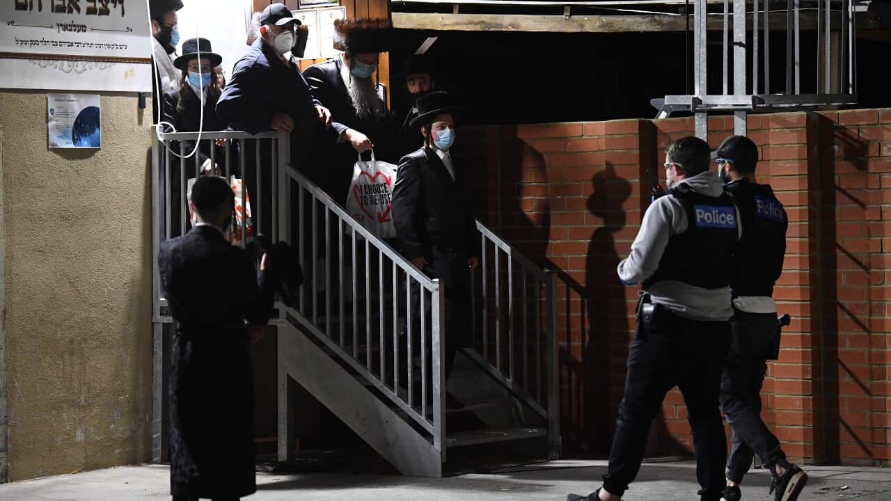Victoria Police are seen as people exit from a building near a Ripponlea synagogue in Melbourne