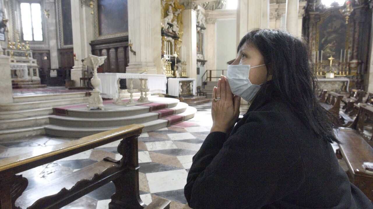 A worshipper prays with a mask on in Italy during the COVID-19 Crisis.