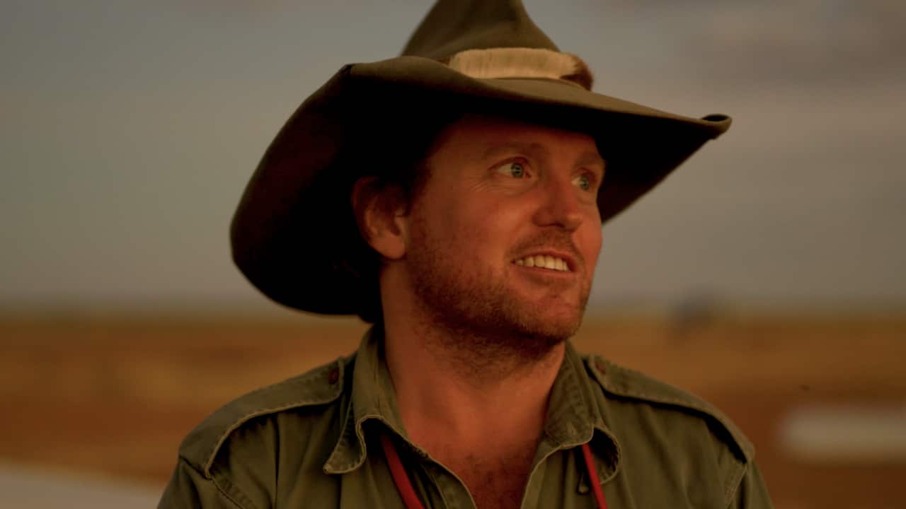 Close up of a man standing outside, wearing a hat