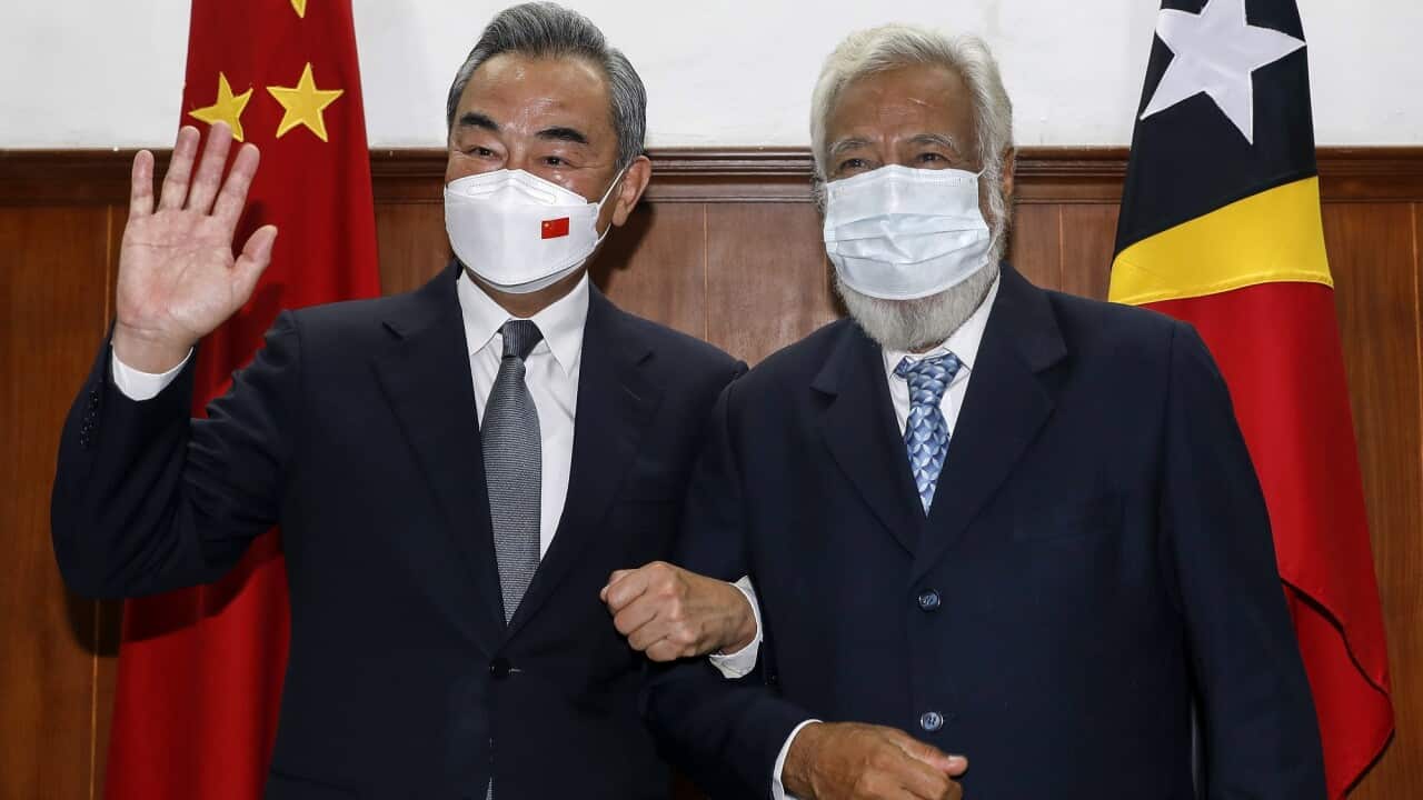 Timor-Leste's Former President Xanana Gusmao (right) and Chinese Foreign Minister Wang Yi (left) smile as they link arms.