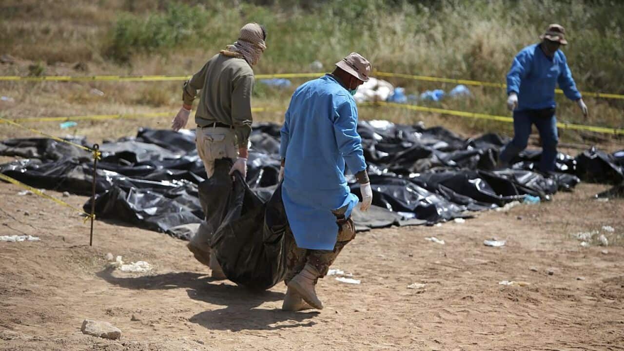Members of the Iraqi security forces work at the site of a mass grave containing the remains of people believed to have been slain by jihadists of the Islamic State (IS) group at the Speicher camp in the city of Tikrit, on April 12, 2015. 