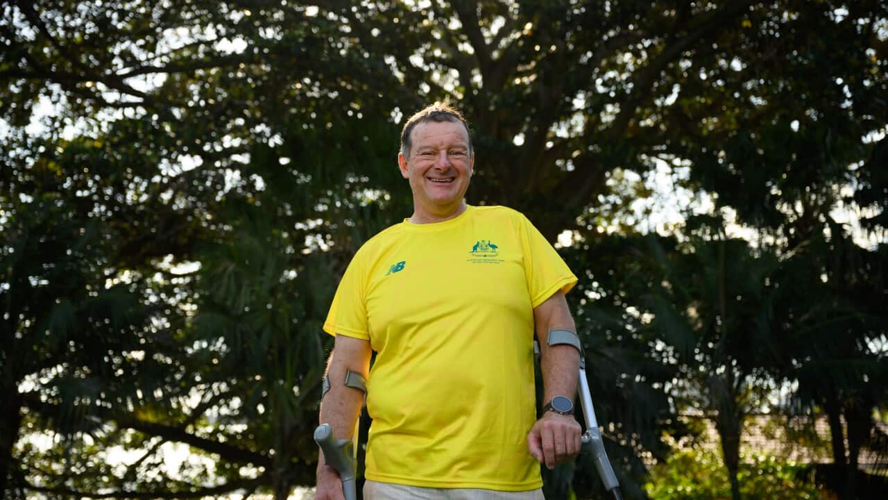 A man wearing a yellow shirt with leg aids smiling.