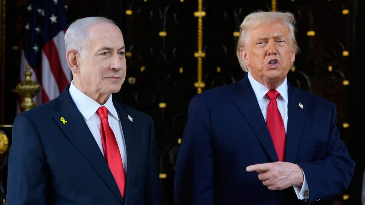 Donald Trump points a finger at Vladimir Putin standing on his right. Both leaders are wearing blue suits with red ties.