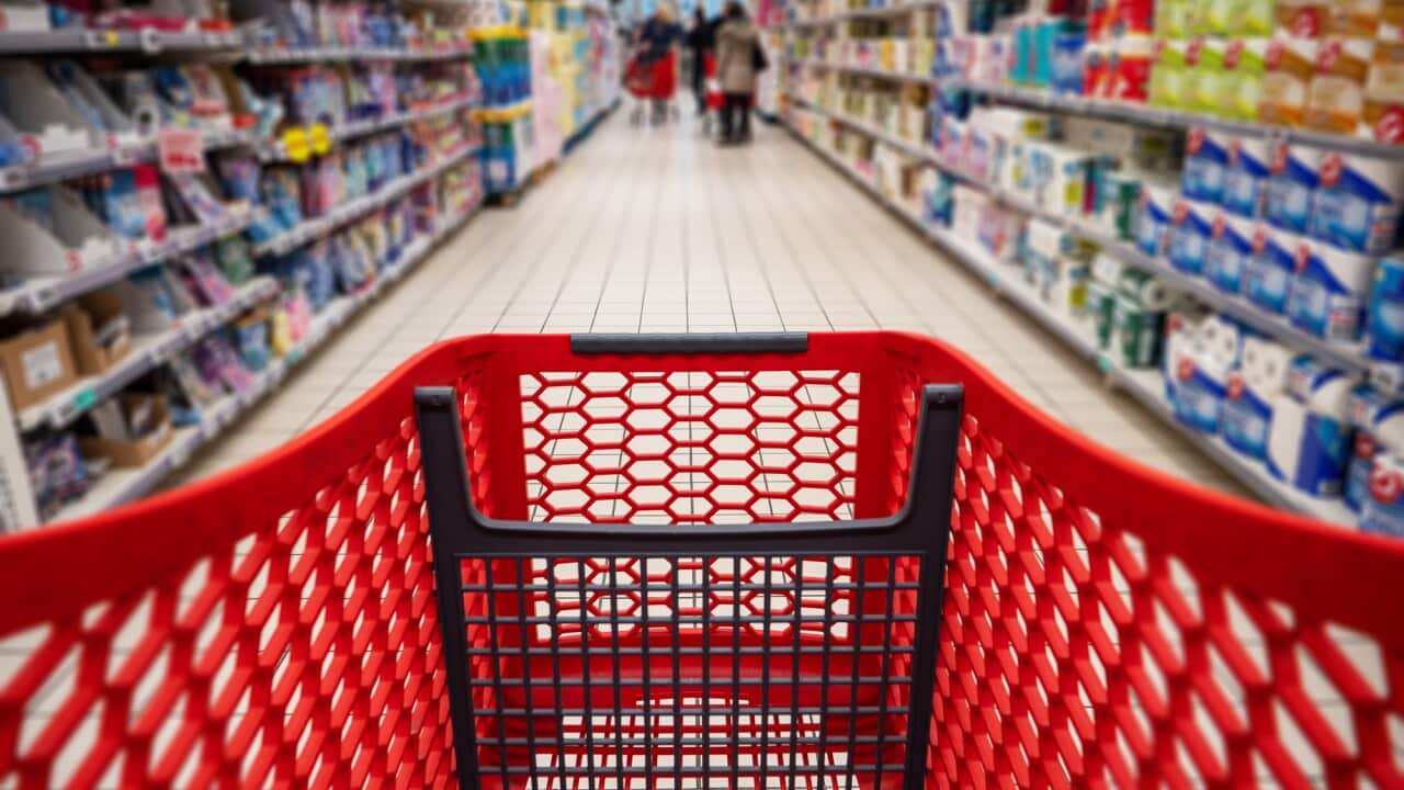 Personal perspective of a shopper pushing shopping trolley along product aisle while shopping in a supermarket. Super Market tinned and canned produce Aisle with Blurred shelves and products to make it generic.