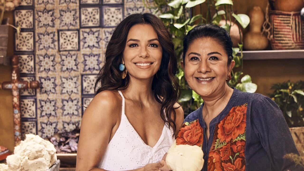 Two women stand in a kitchen, smiling. 