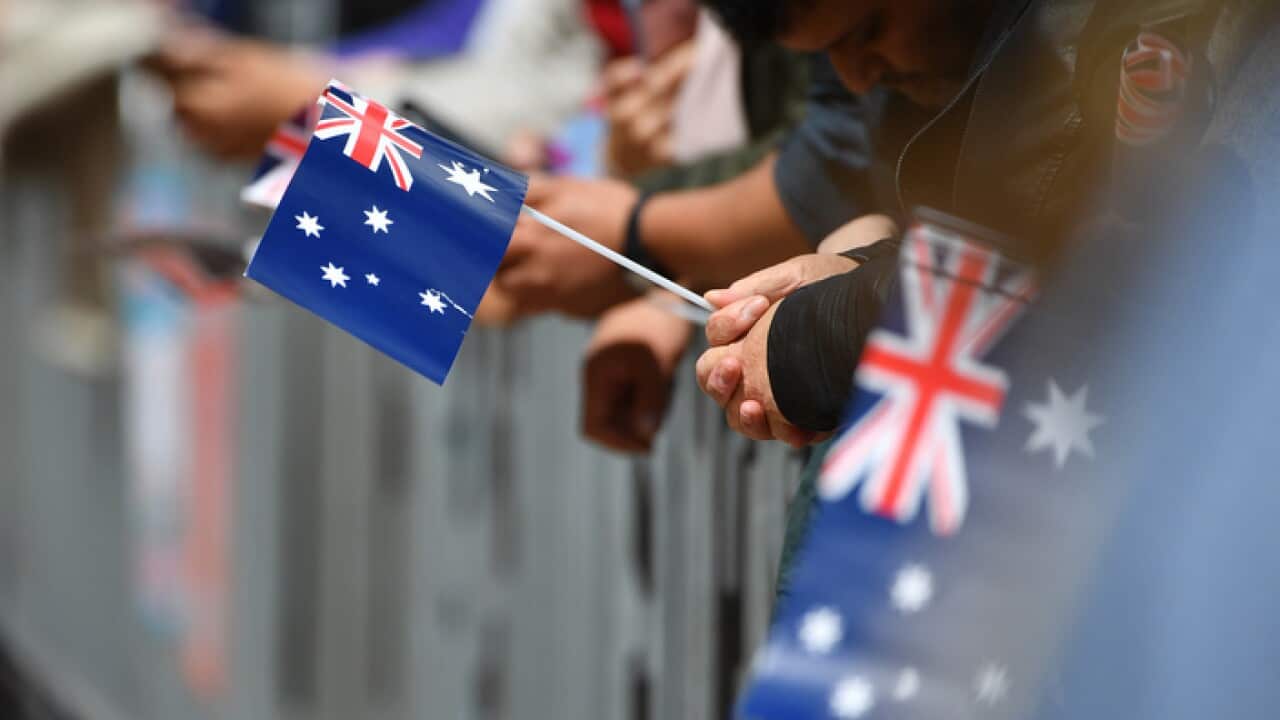 Australian flags held by royal fans are seen as Britain's Prince Harry, the Duke of Sussex, and his wife Meghan, the Duchess of Sussex, conduct a meet the people walk at the Sydney Opera House in Sydney
