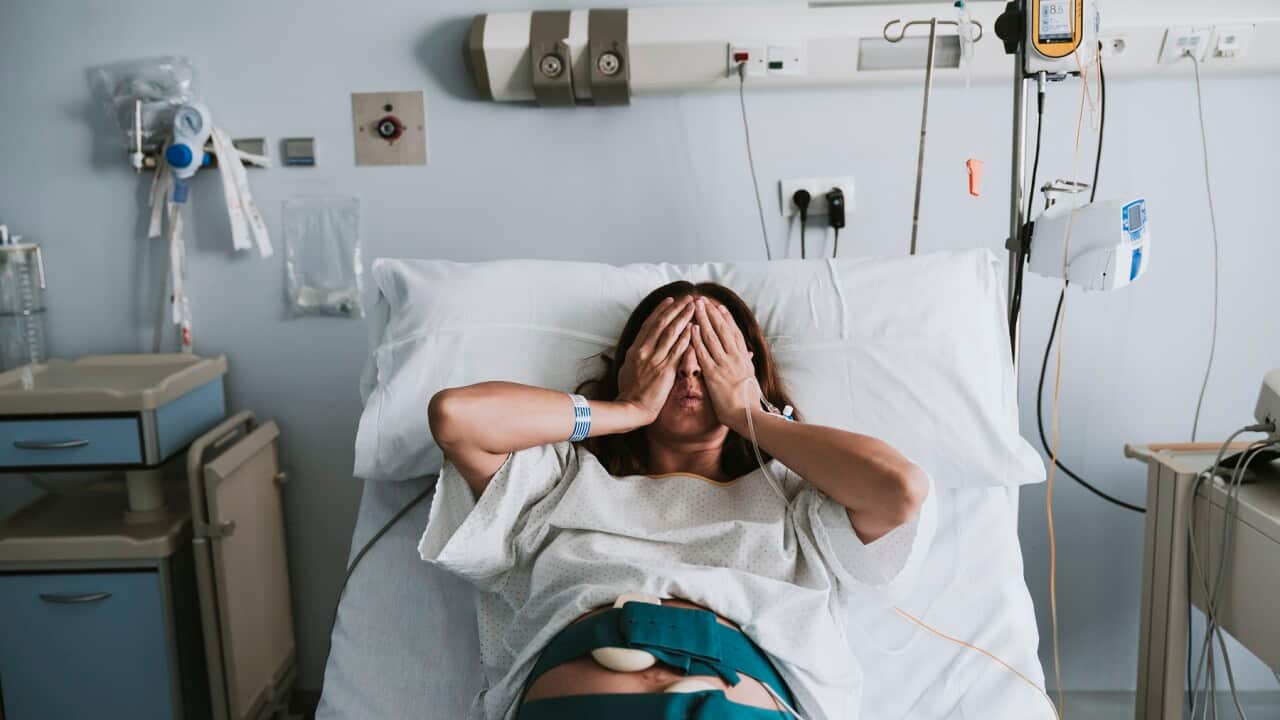 Stressed pregnant woman lying on bed in hospital