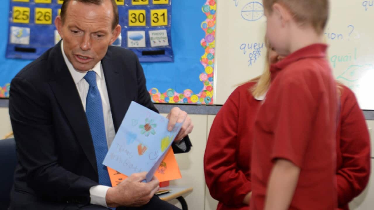 Opposition Leader Tony Abbott displays a card given to him by students