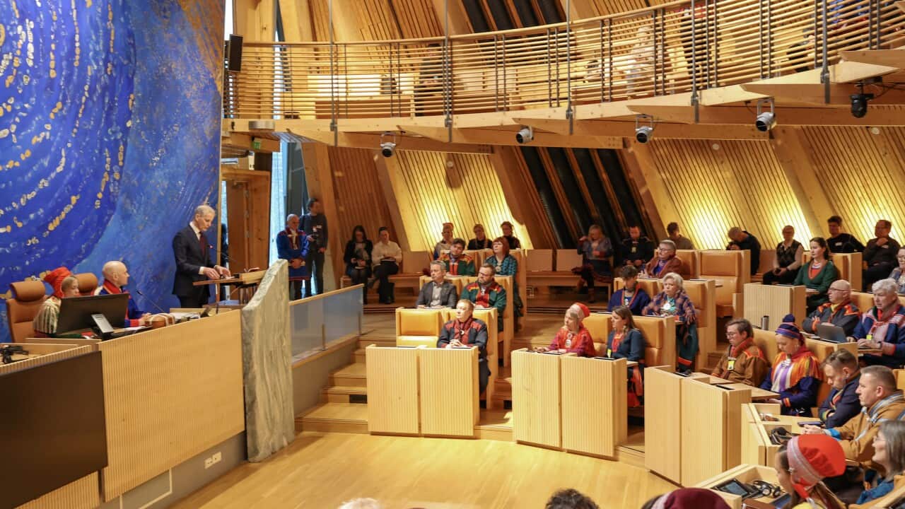 Delegates seated in a semi-circle facing a speaker in the Sámi Parliament building.