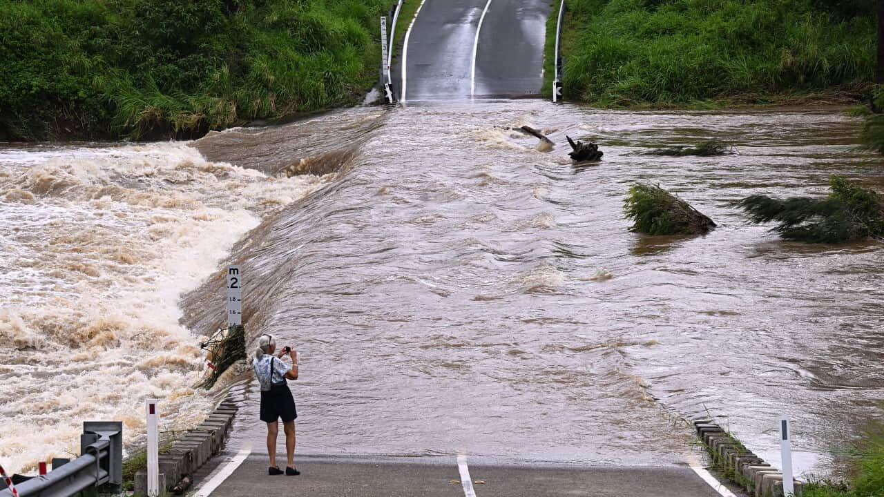 A woman standing in front of a flooded road