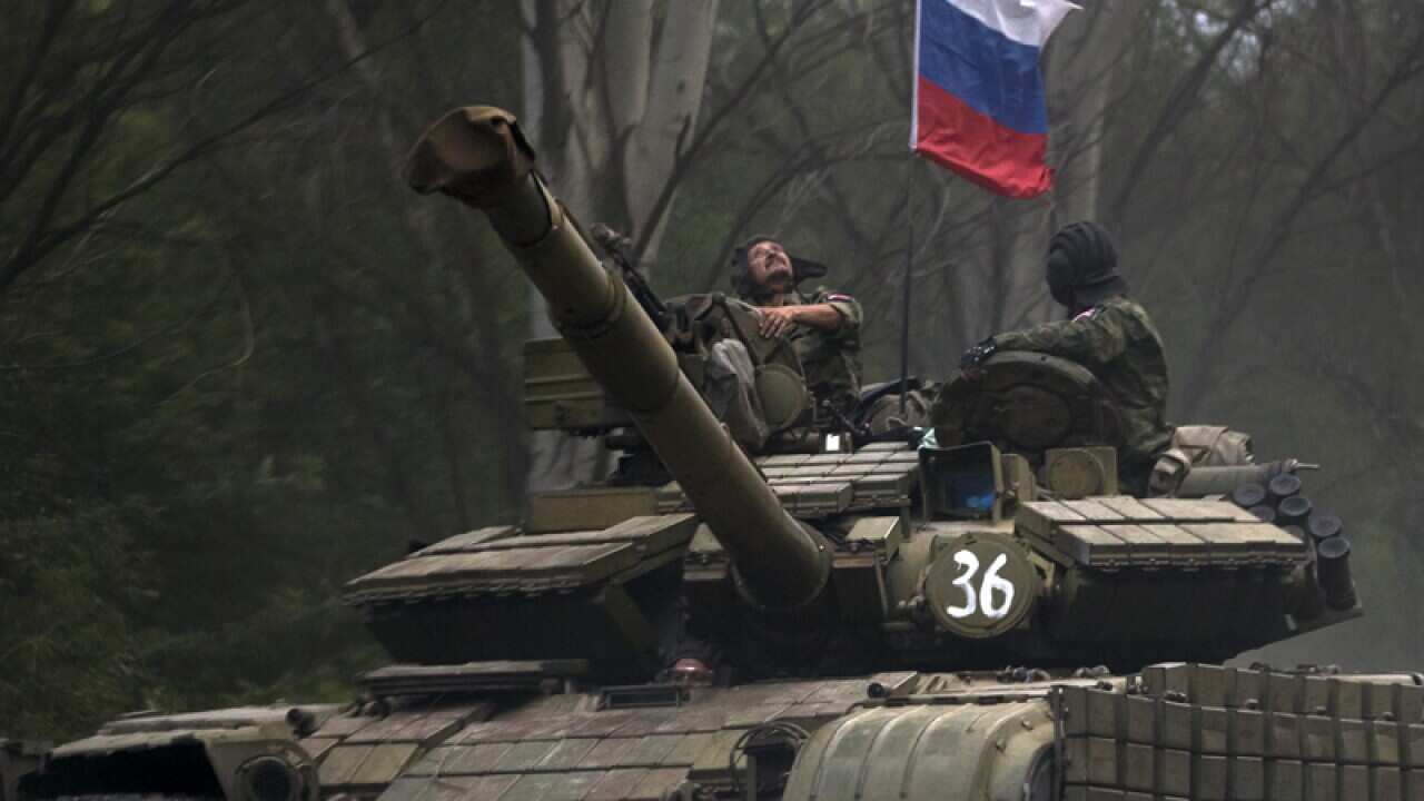 A pro-Russian rebel looks up while ridding on a tank