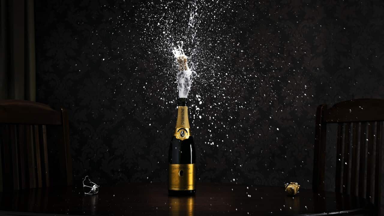 bottle of champagne on table exploding cork