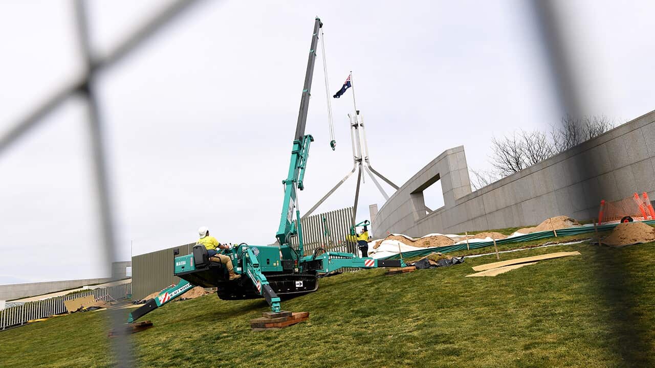 Workers are seen putting up new fence panels 