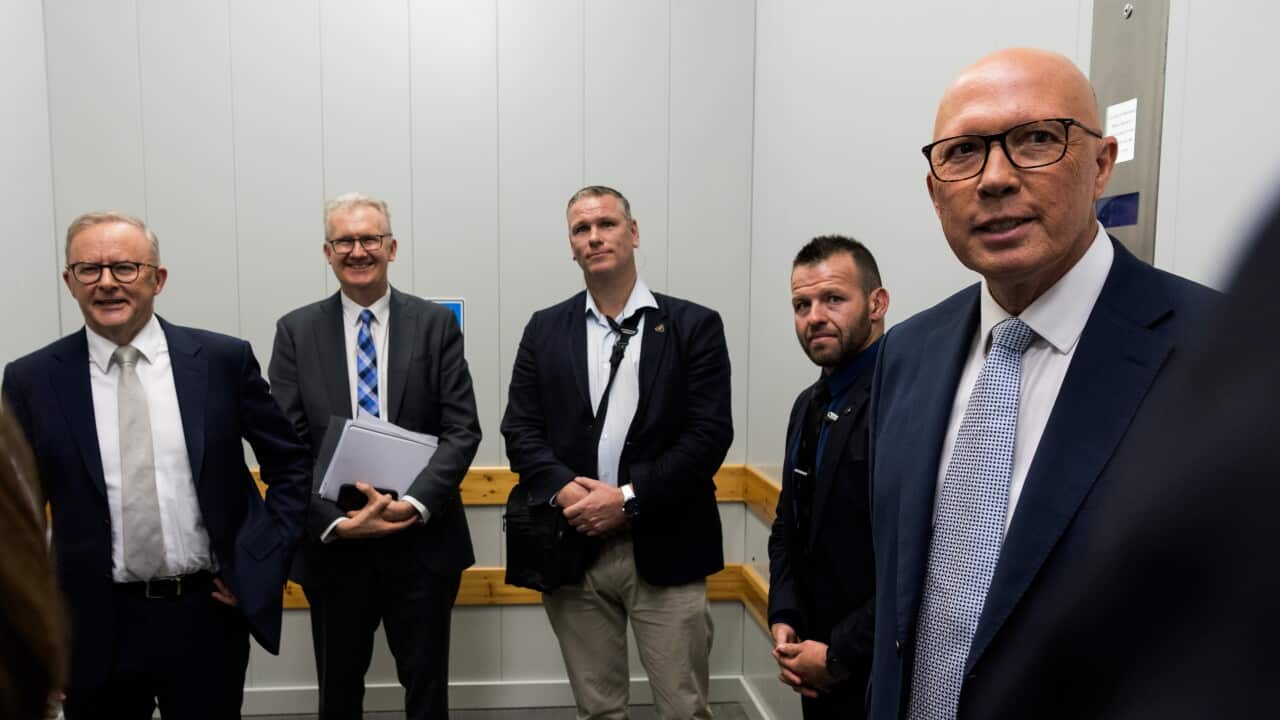 A group of men, including Anthony Albanese and Peter Dutton, stand in a lift. All are wearing suit jackets.
