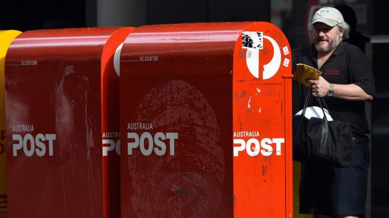 A man is seen posting a parcel at an Australia Post box in Sydney, Monday, July 13, 2015. (AAP Image/Mick Tsikas) NO ARCHIVING