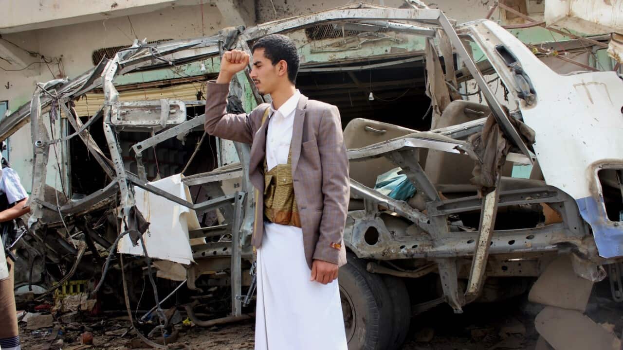 A Yemeni stands near a destroyed bus at the site of a Saudi-led airstrike.