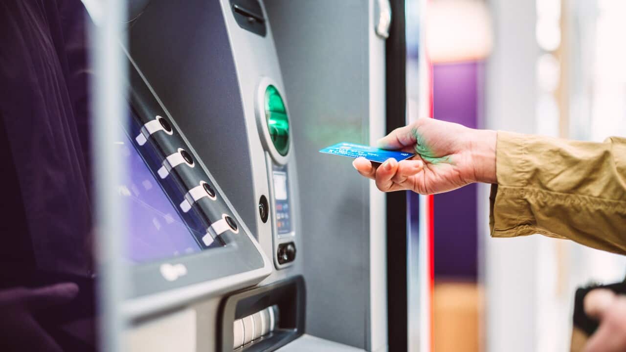 Female hand inserting bank card into automatic cash machine.