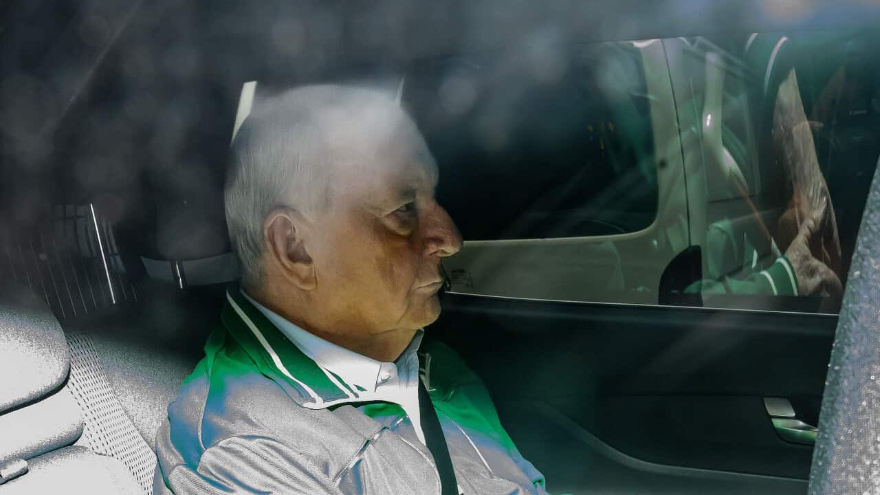 A blurred image of an elderly man sitting in a car.