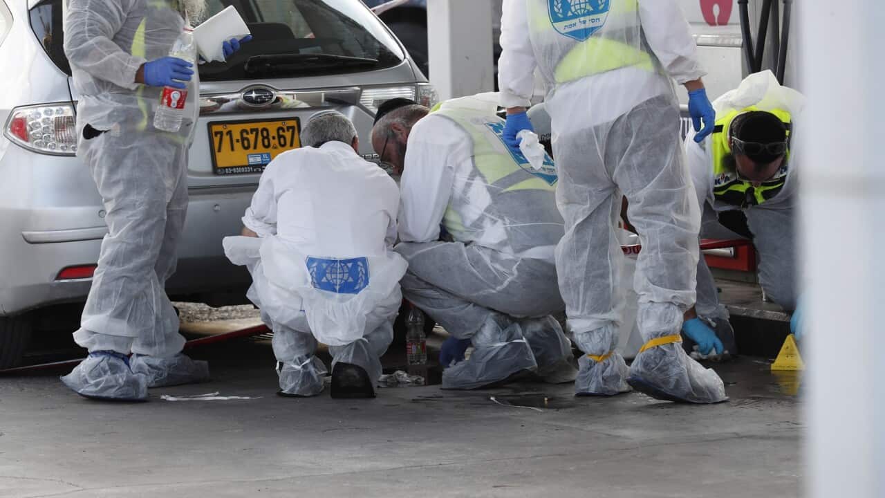 Israeli security forces officers and medicals investigate next to a body of a victim at the scene of a shooting in the settlement of Eli