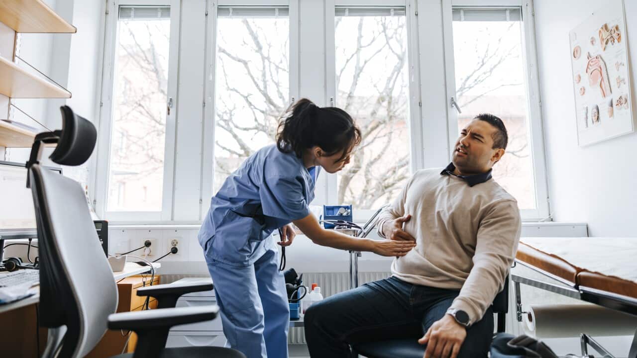 Female healthcare worker examining stomachache of male patient in medical examination room