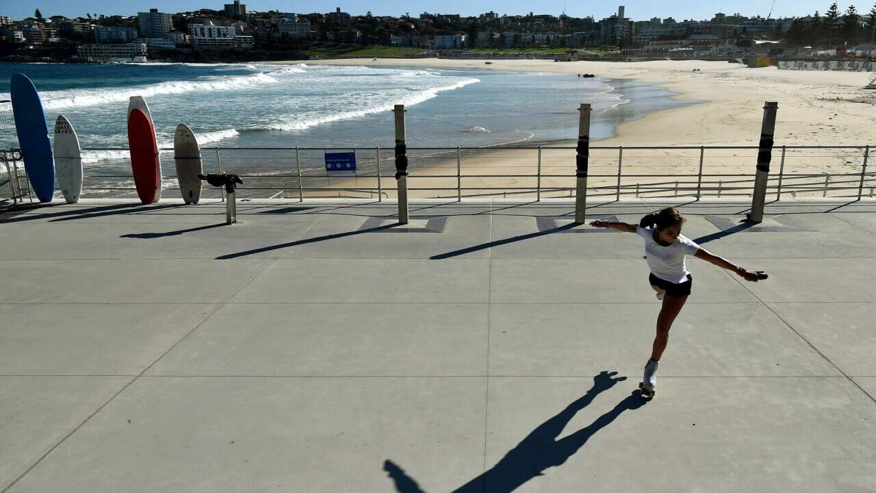 A woman roller skates in front of a closed Bondi Beach in Sydney, Sunday, April 12, 2020. (AAP Image/Joel Carrett) NO ARCHIVING