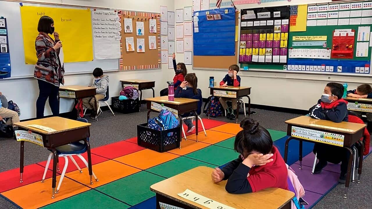 In this Jan. 29, 2021 file photo, Victoria Vo raises her hand, background center, in the back of Hannah Thrower's kindergarten class at Alice Smith Elementary School in Reno, Nev. U.S. guidelines that say students should be kept 6 feet apart in schools ar