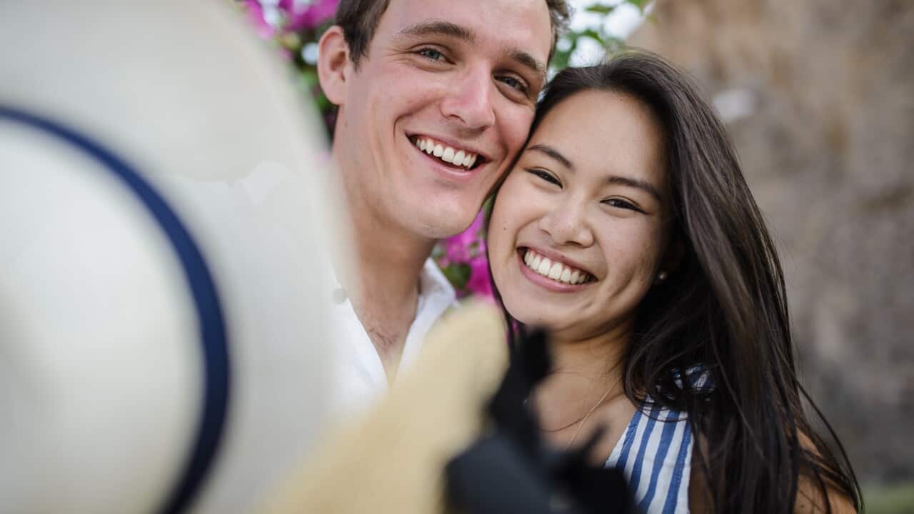 Young couple walking in the background of a large bush