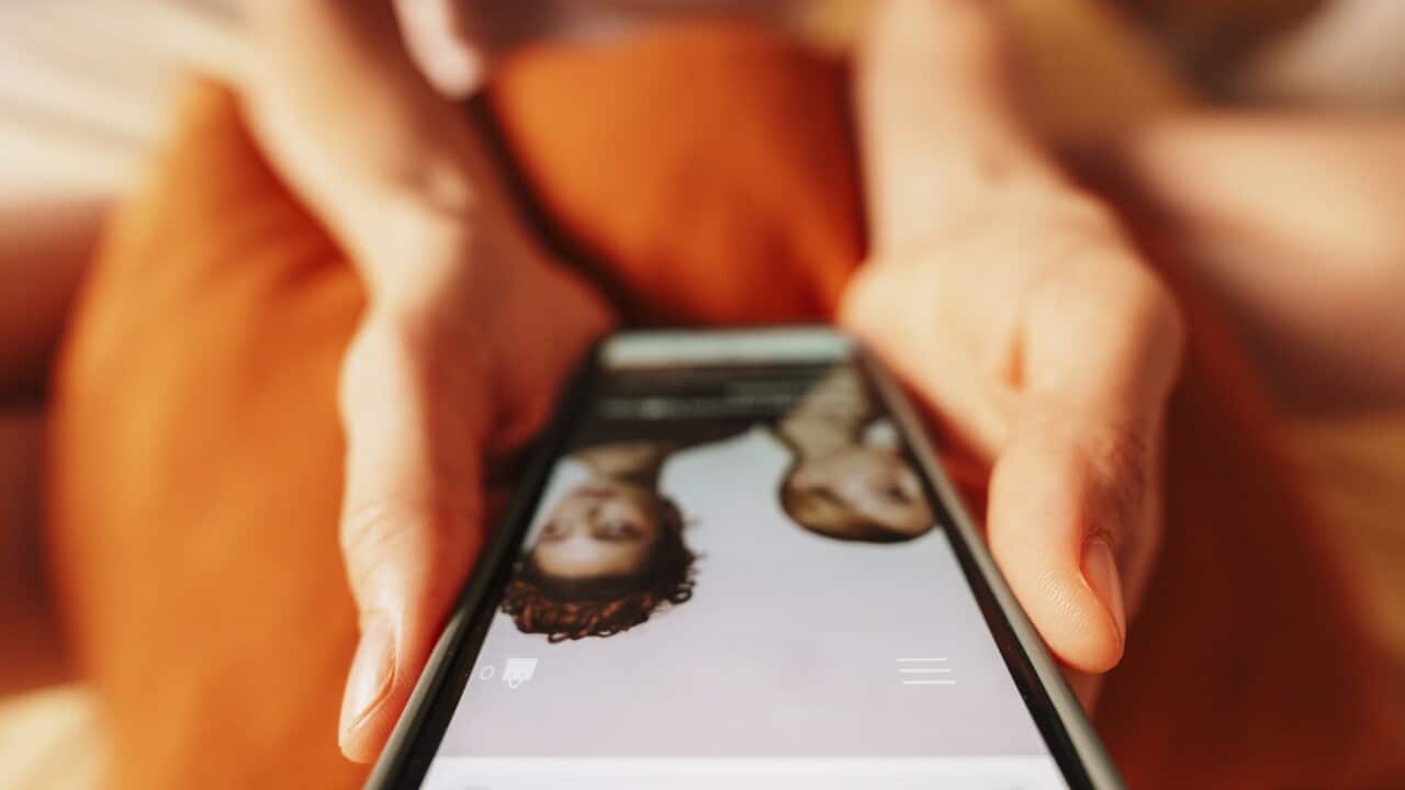 Hand holding smartphone shopping online at home in casual setting