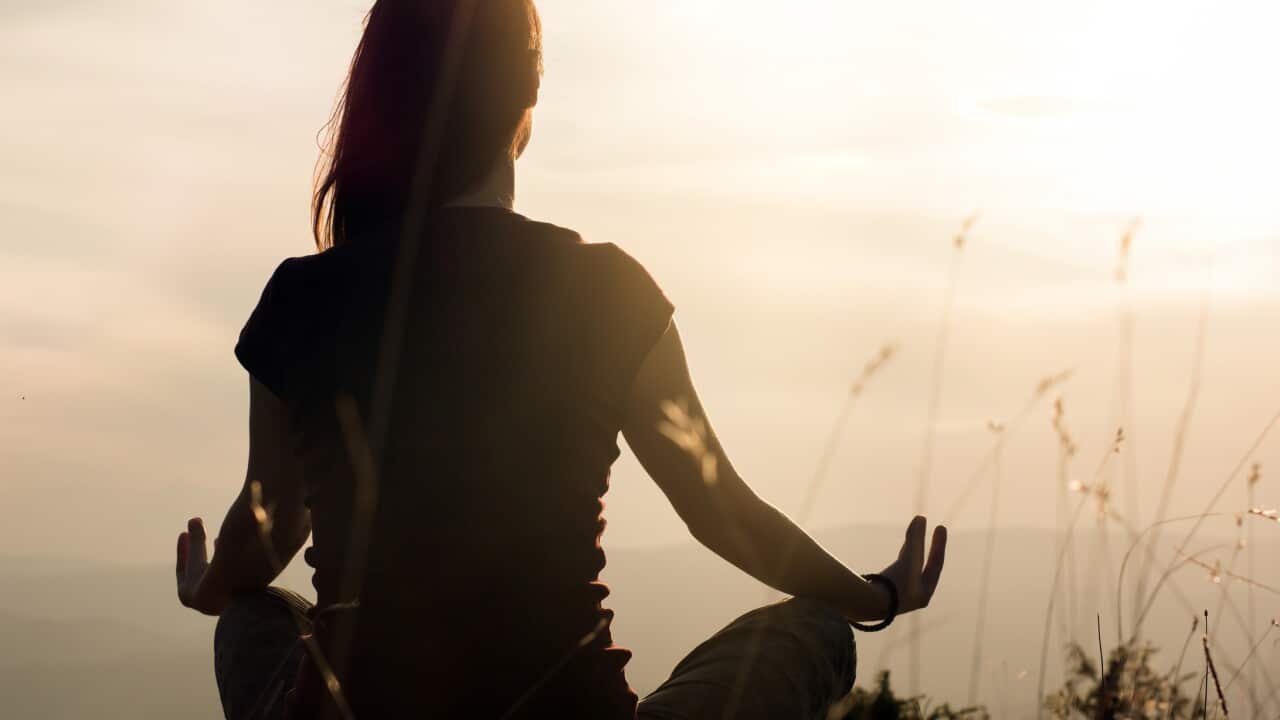 Silhouette of young woman practicing yoga outdoors