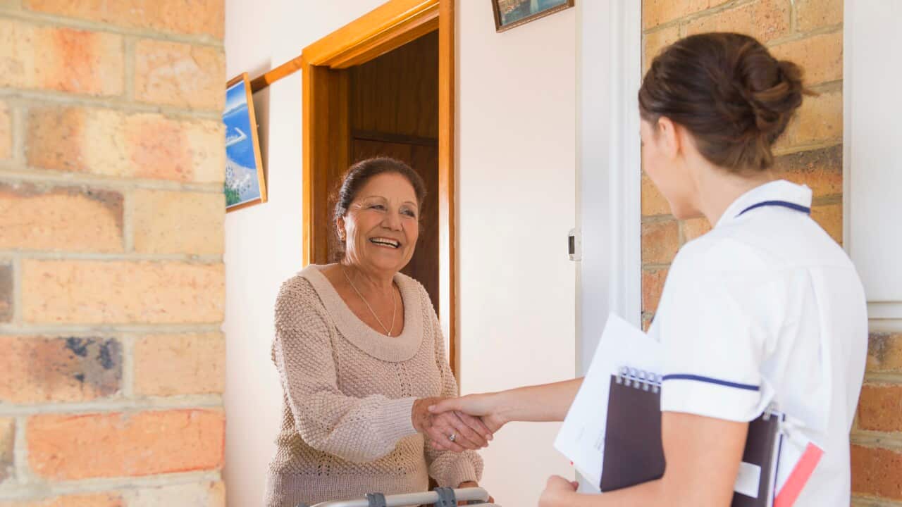 Hispanic woman greeting nurse in doorway