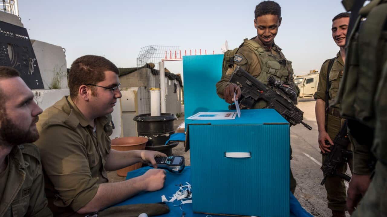 Israeli soldiers cast their ballots oat a mobile voting booth, two days before polling stations open in the rest of Israel, at a military post on the northern Israel and Gaza border, Sunday, April 7, 2019. (AP Photo/Tsafrir Abayov)
