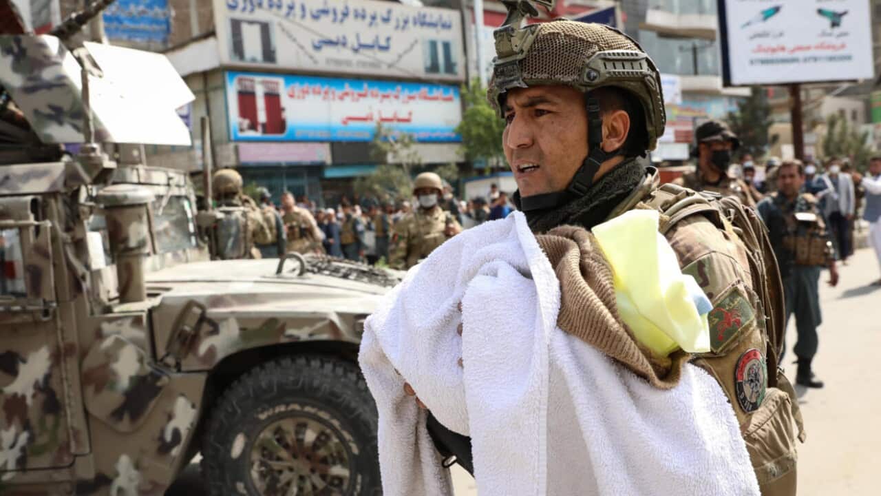 A soldier holds a baby at the scene of an attack at a Doctors without Borders hospital in Kabul, Afghanistan, 12 May 2020. 
