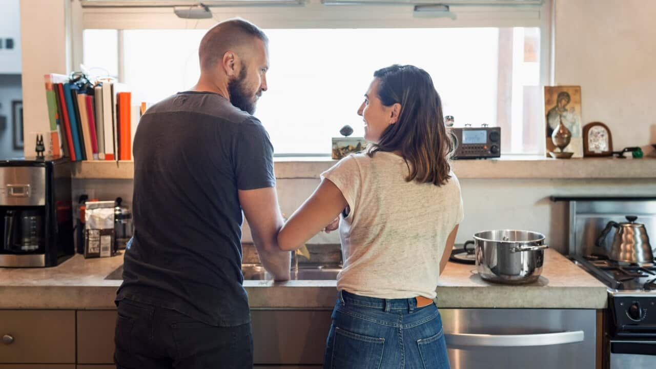 Rear view of couple looking at each other in kitchen