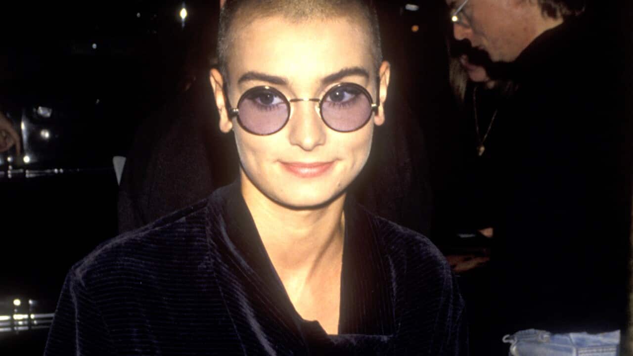 Sinead O'Connor wearing a black gown and glasses.