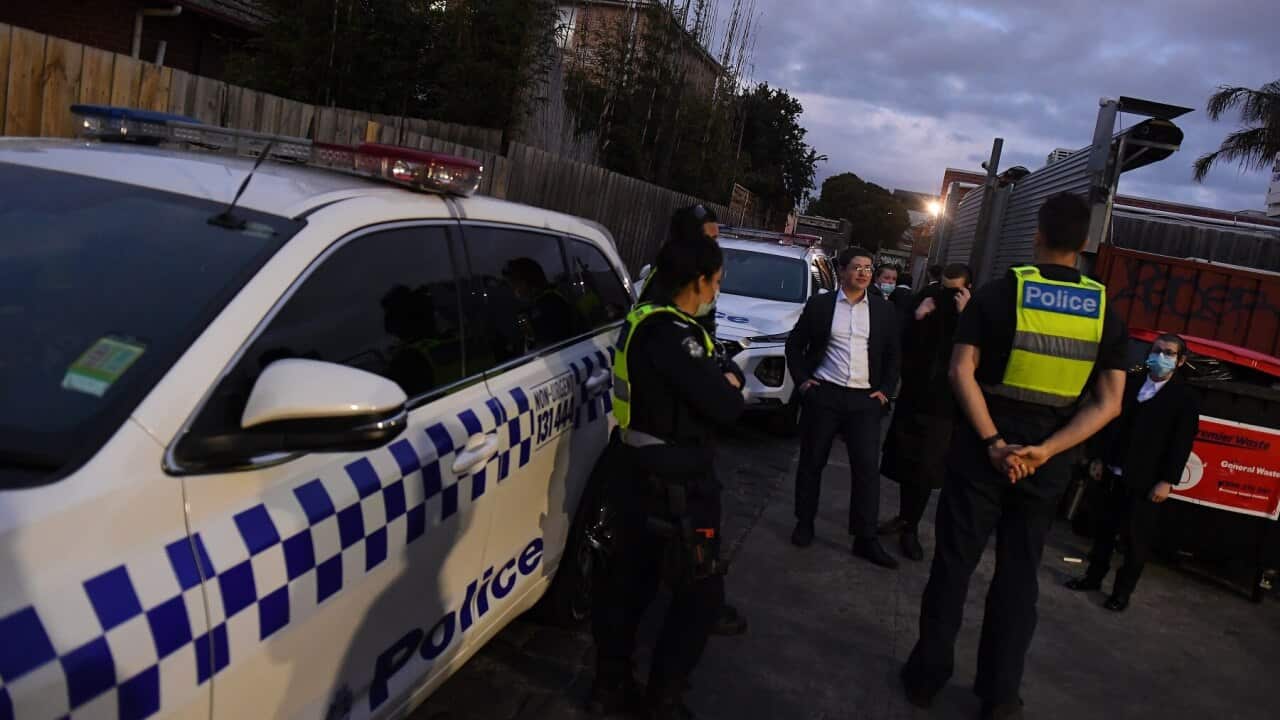 People speak with Victorian Police outside of a building near a Ripponlea synagogue in Melbourne