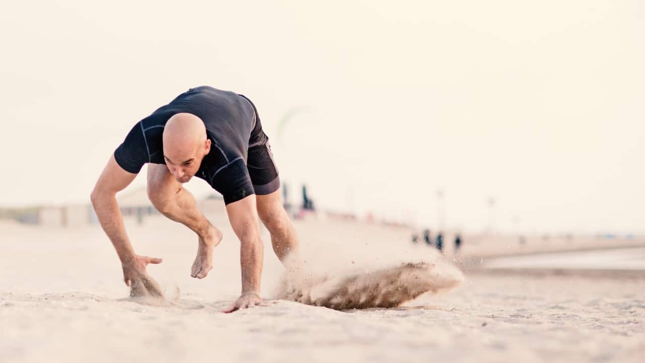 Handsome shaved athletic male working out on sandy beach