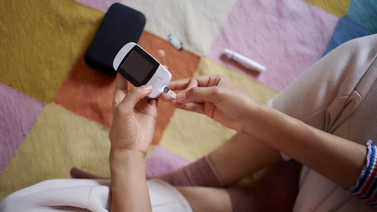 Young woman measuring her blood sugar using glucometer (Getty).