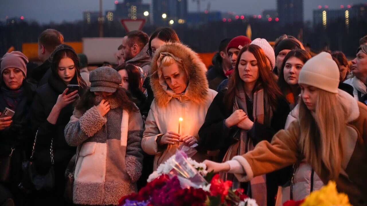 Women dressed in winter coats laying flowers at a memorial