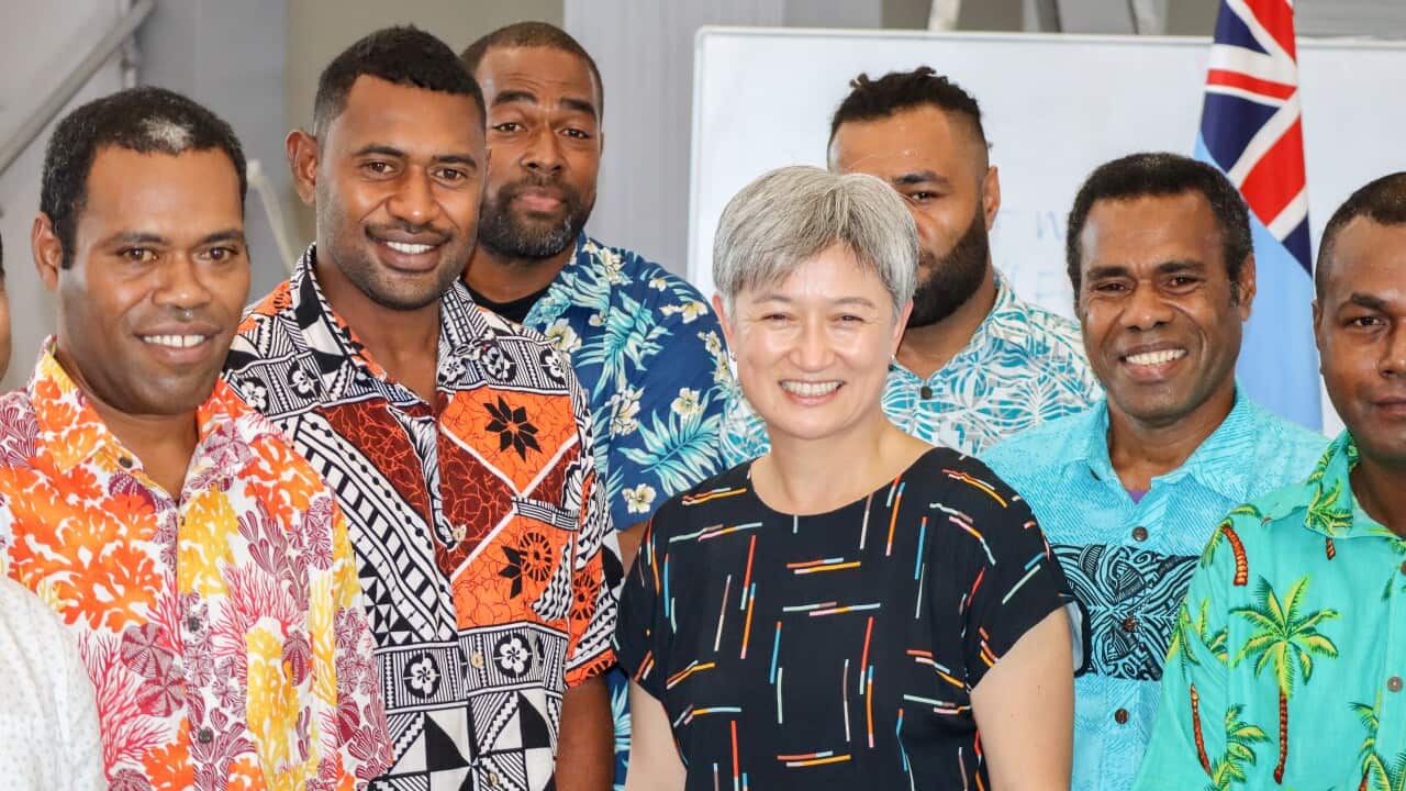 Penny Wong surrounded by a group of Fijian men
