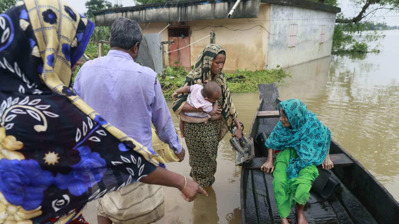 People try to get on a wooden boat to escape flood waters.