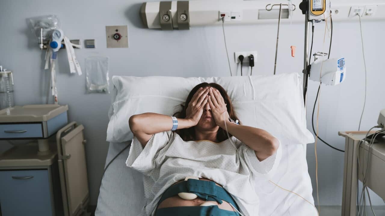 Stressed pregnant woman lying on bed in hospital
