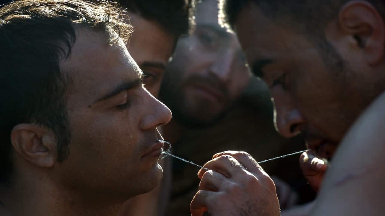 A migrant stitches the lips of a fellow migrant from Iran in an act of protest against restrictions imposed by Balkan countries on the movement of migrants near Gevegelija, The Former Yugoslav Republic of Macedonia, 23 November 2015. (EPA/GEORGI LICOVSKI)