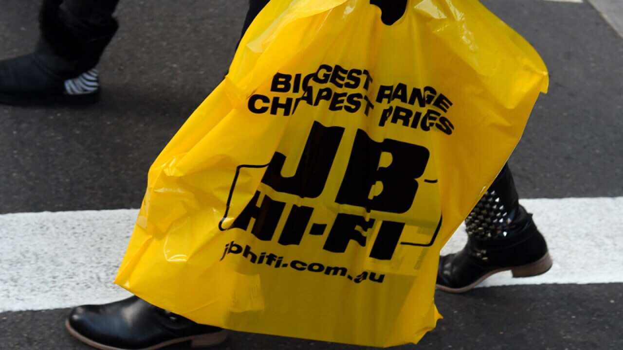 A patron leaves a JB Hi-Fi store with a purchase in Sydney