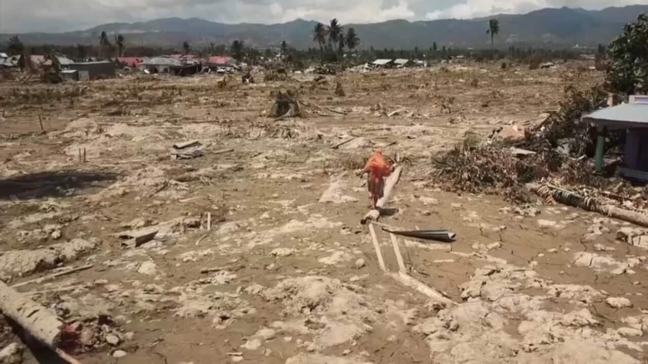 Surianto walks over the mud that engulfed her home