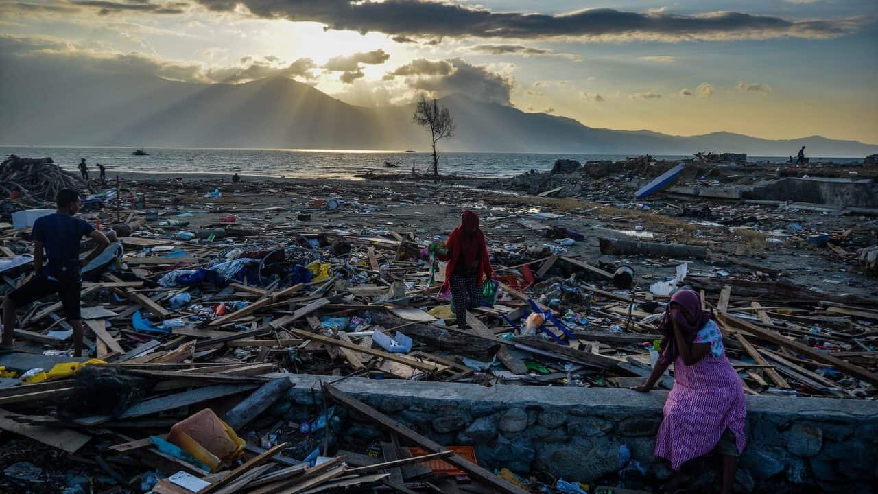 Indonesians stand among debris at Mamboro village in Palu, Central Sulawesi.