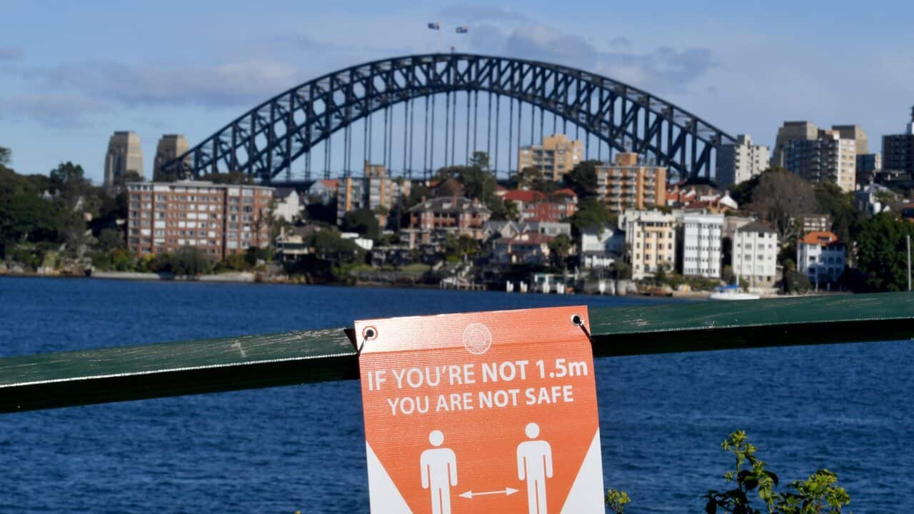 A sign warning people to socially distance is seen on the foreshore in front of the Sydney Harbour Bridge on Friday, 16 July, 2021.