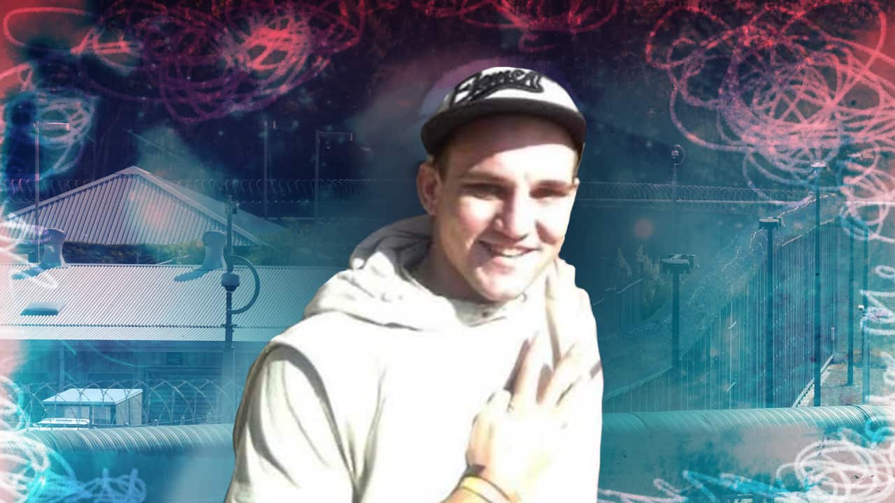 A young man wearing a cap and hoodie smiles.